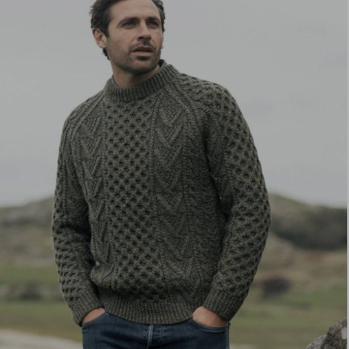 A man in a sweater standing on top of a hill.