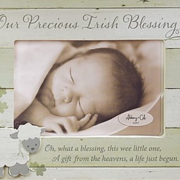 A baby is laying down in front of a picture frame.