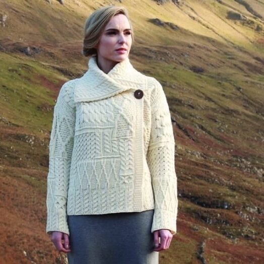 A woman in white sweater standing on top of hill.